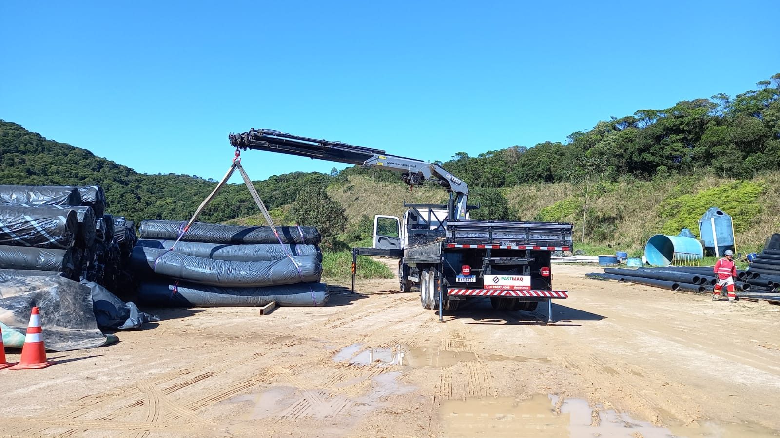Munck descarregando tubos em obra de saneamento