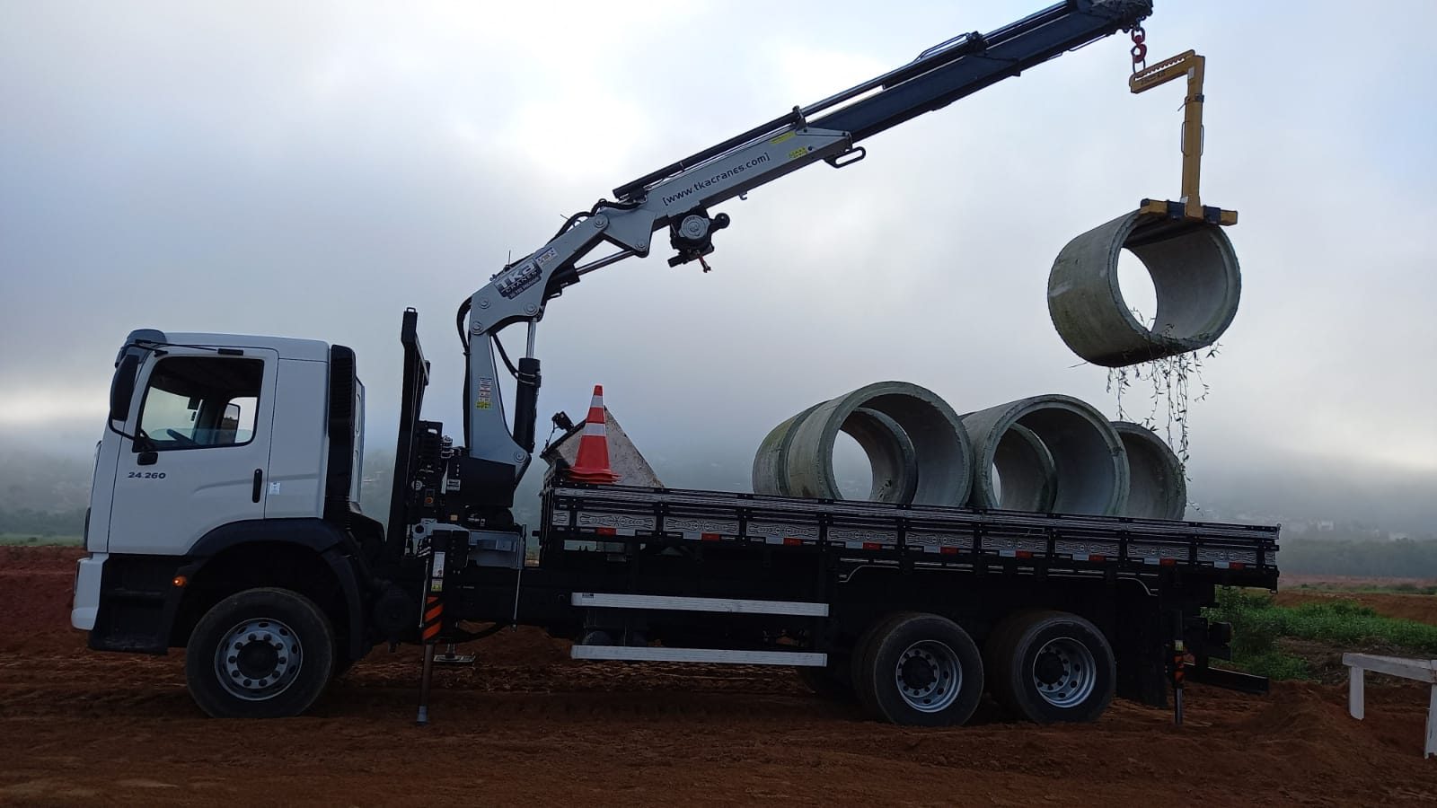 Munck da PastMaq içando tubo de concreto sobre a carroceria