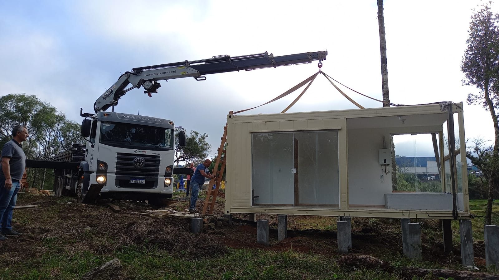 Munck posicionando módulo habitacional sobre a base