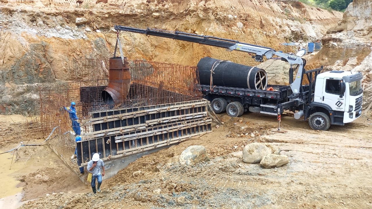 Munck posicionando tubulação dentro de escavação